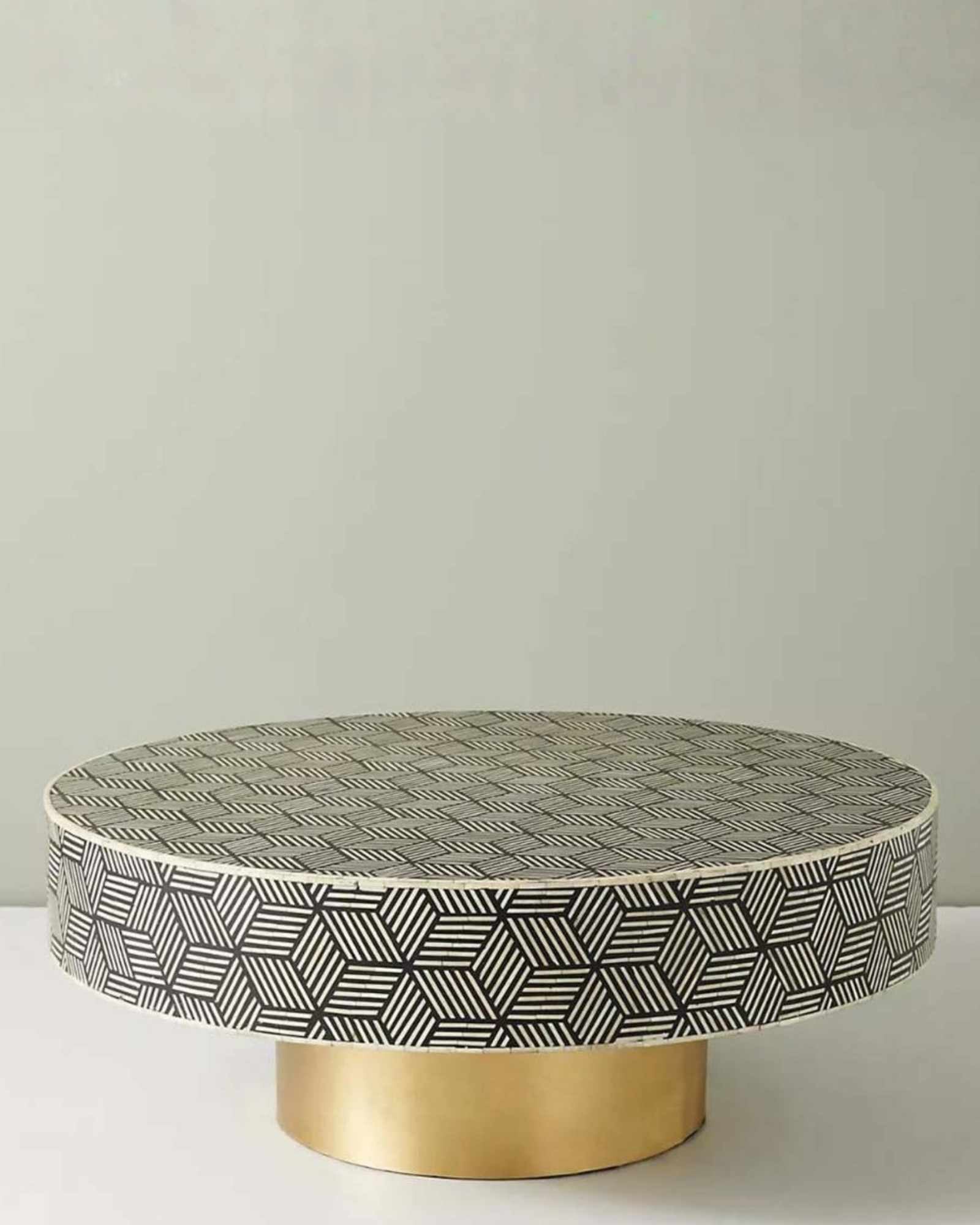 Round black bone inlay coffee table with a bold geometric pattern and gold base. A modern centerpiece for elegant living spaces.