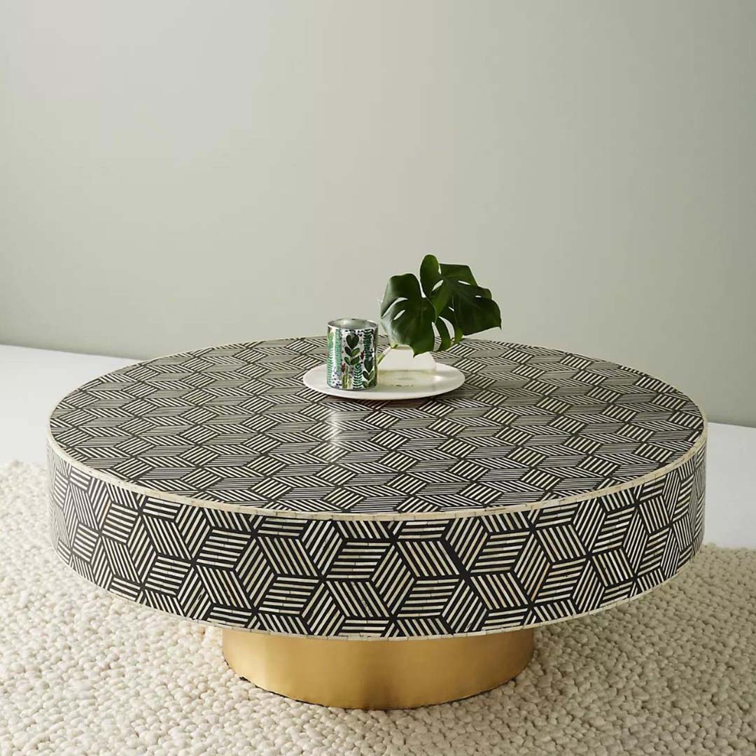 Round black bone inlay coffee table with a bold geometric pattern and gold base. A modern centerpiece for elegant living spaces.