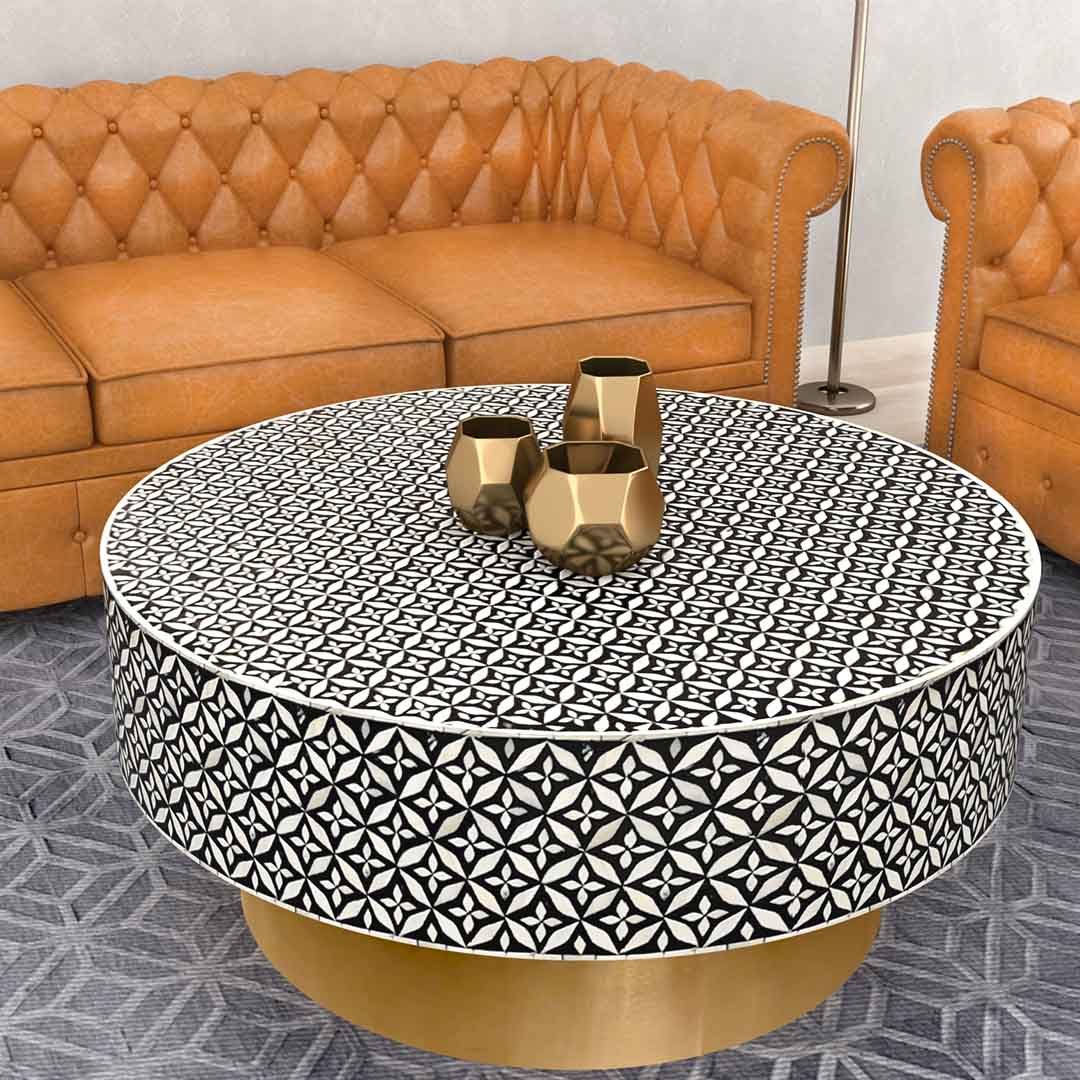 Round black bone inlay coffee table with intricate floral pattern and bold gold base. A modern, stylish centerpiece for any room.