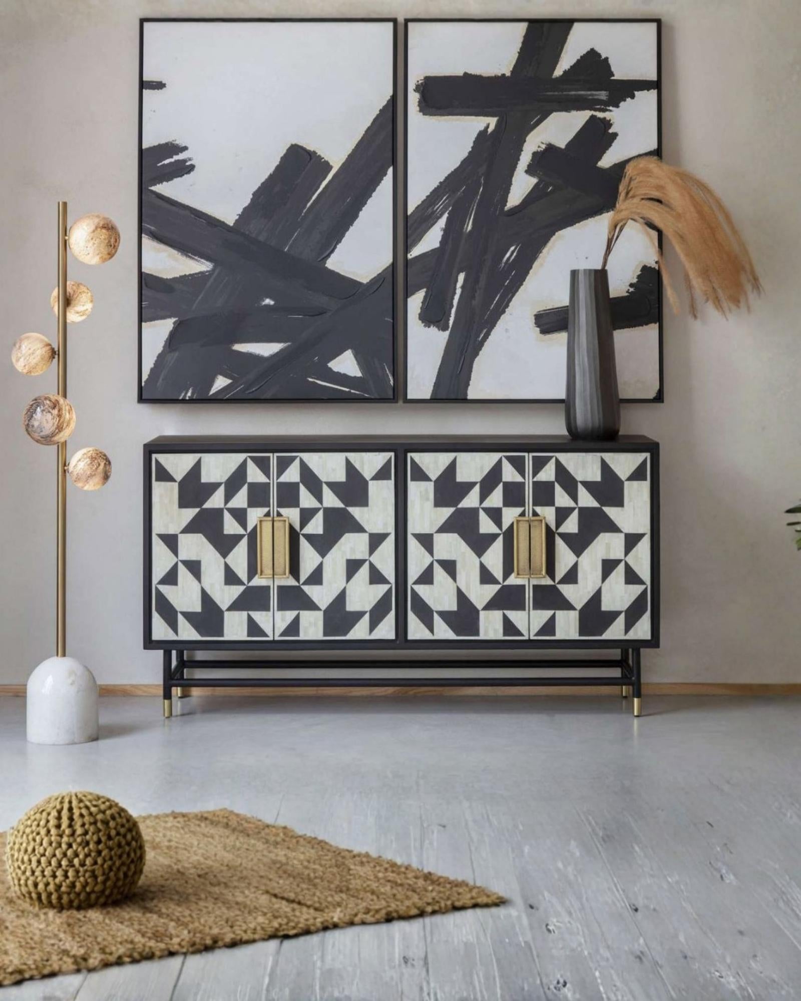 Elegant black bone inlay cabinet with geometric patterns, gold handles, and slim legs, perfect for a statement living space.