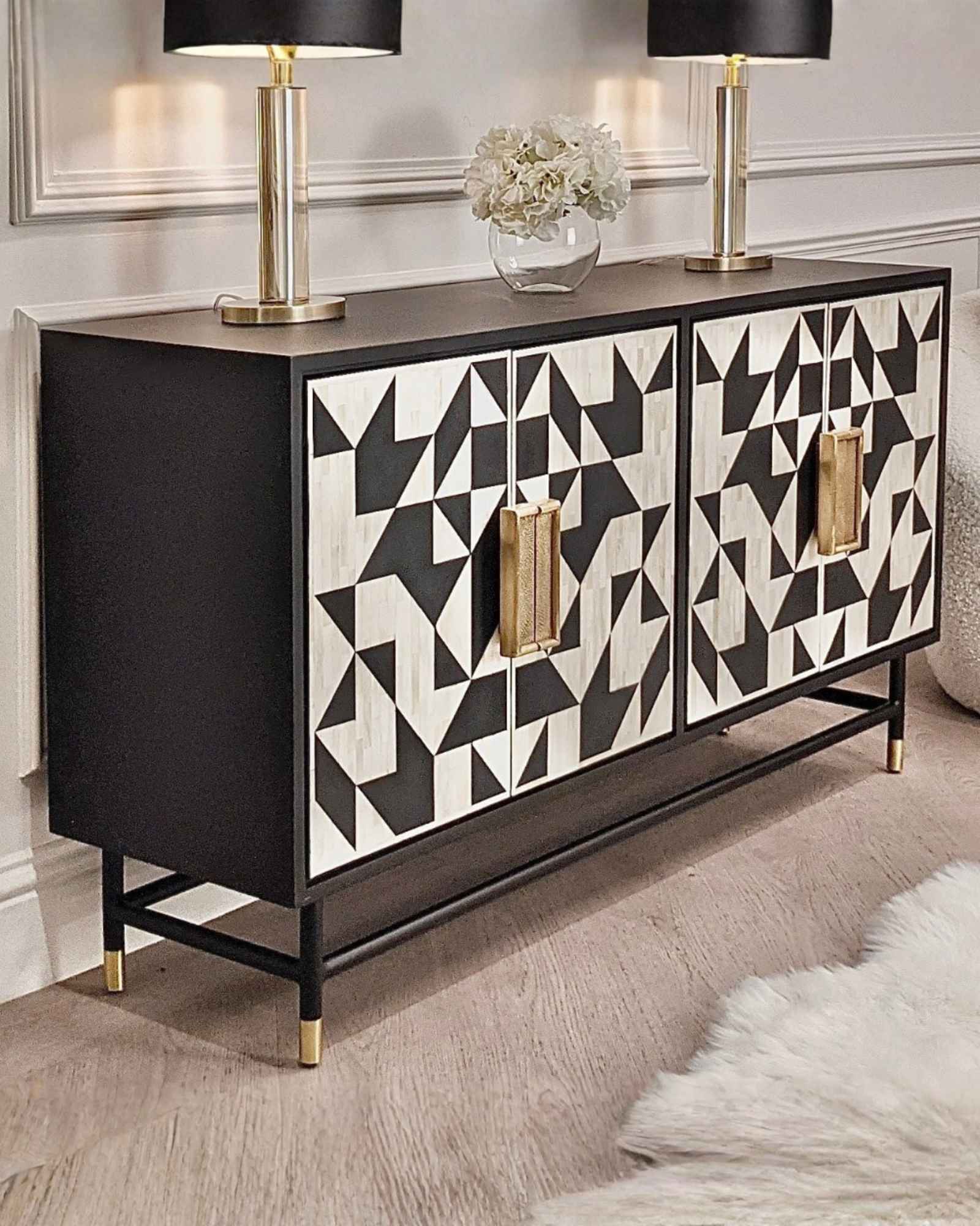 Elegant black bone inlay cabinet with geometric patterns, gold handles, and slim legs, perfect for a statement living space.