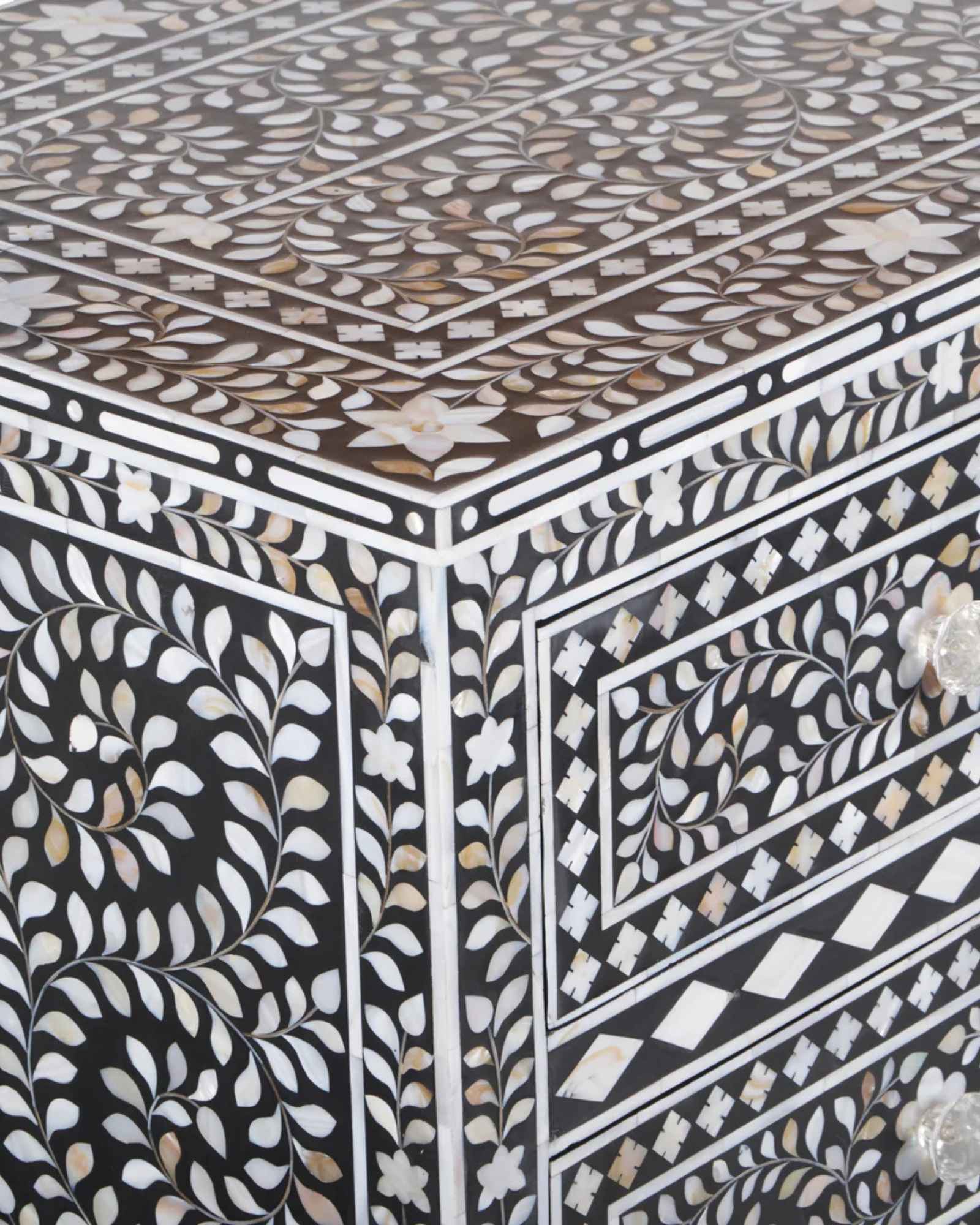 A handcrafted black mother of pearl inlay chest of drawers, featuring intricate floral patterns and geometric designs, with crystal knobs and smooth drawer slides.