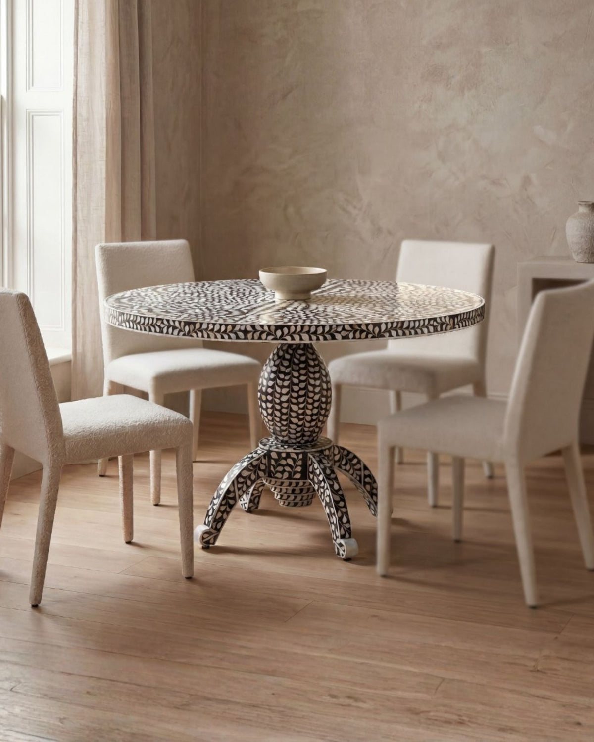 Handcrafted Iris dining table featuring black mother of pearl inlay with a round top and sculptural pedestal base.