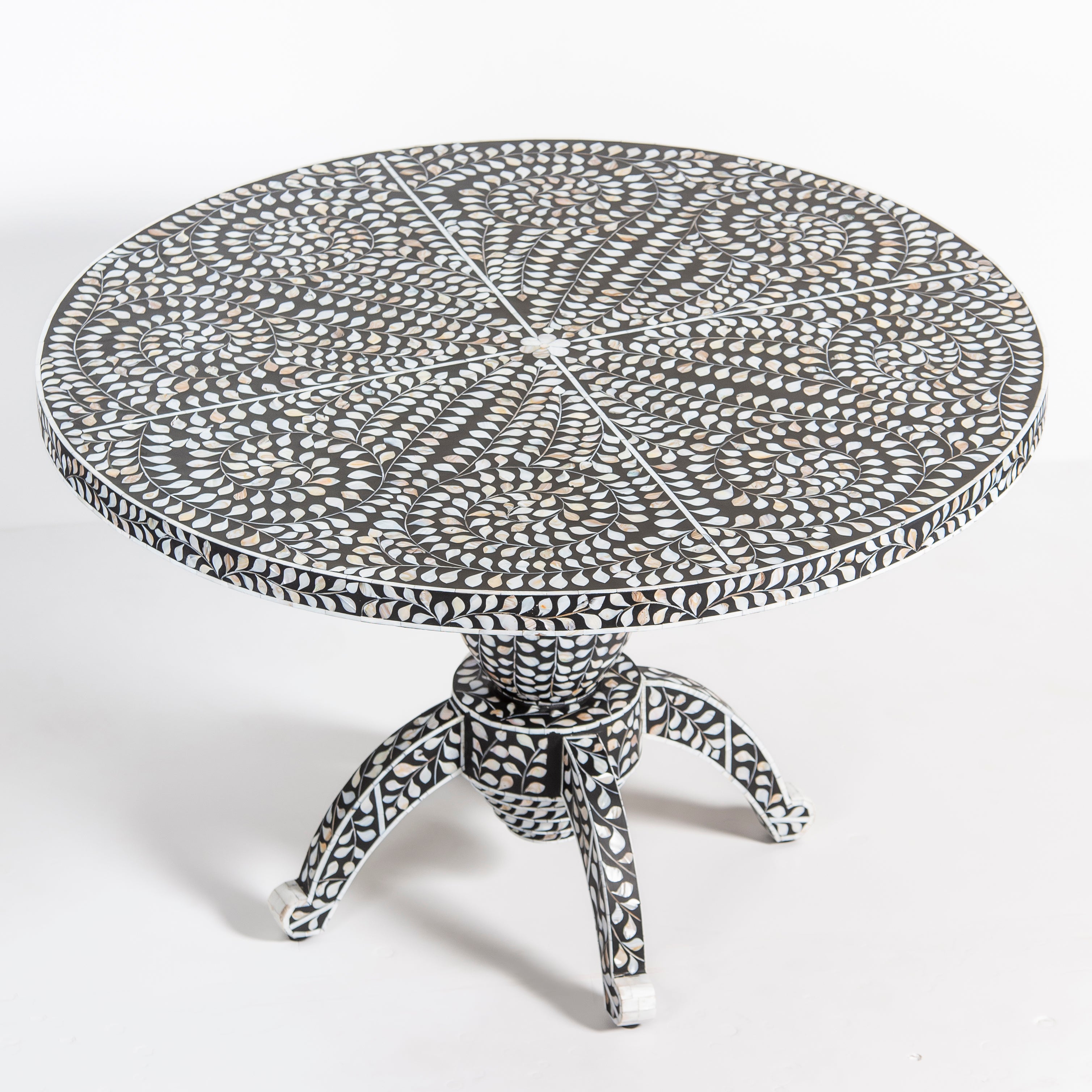 Handcrafted Iris dining table featuring black mother of pearl inlay with a round top and sculptural pedestal base.