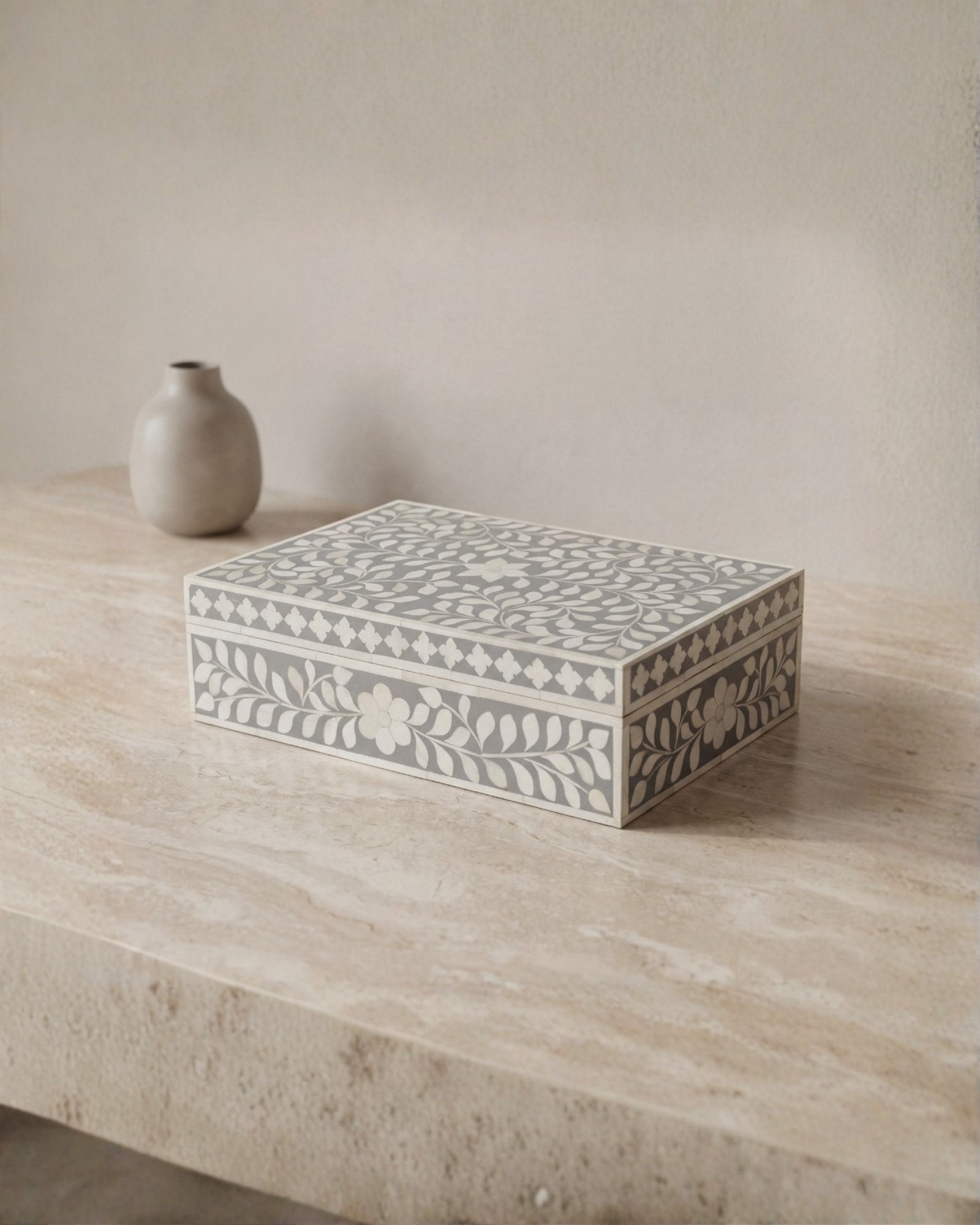A soft grey decorative box crafted in bone inlay, combining subtle tones with intricate floral detailing.