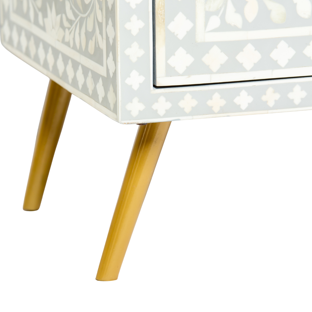 Grey bone inlay cabinet with floral vine pattern, brass legs, and carved bone knobs, handcrafted with spacious storage and artisanal charm.