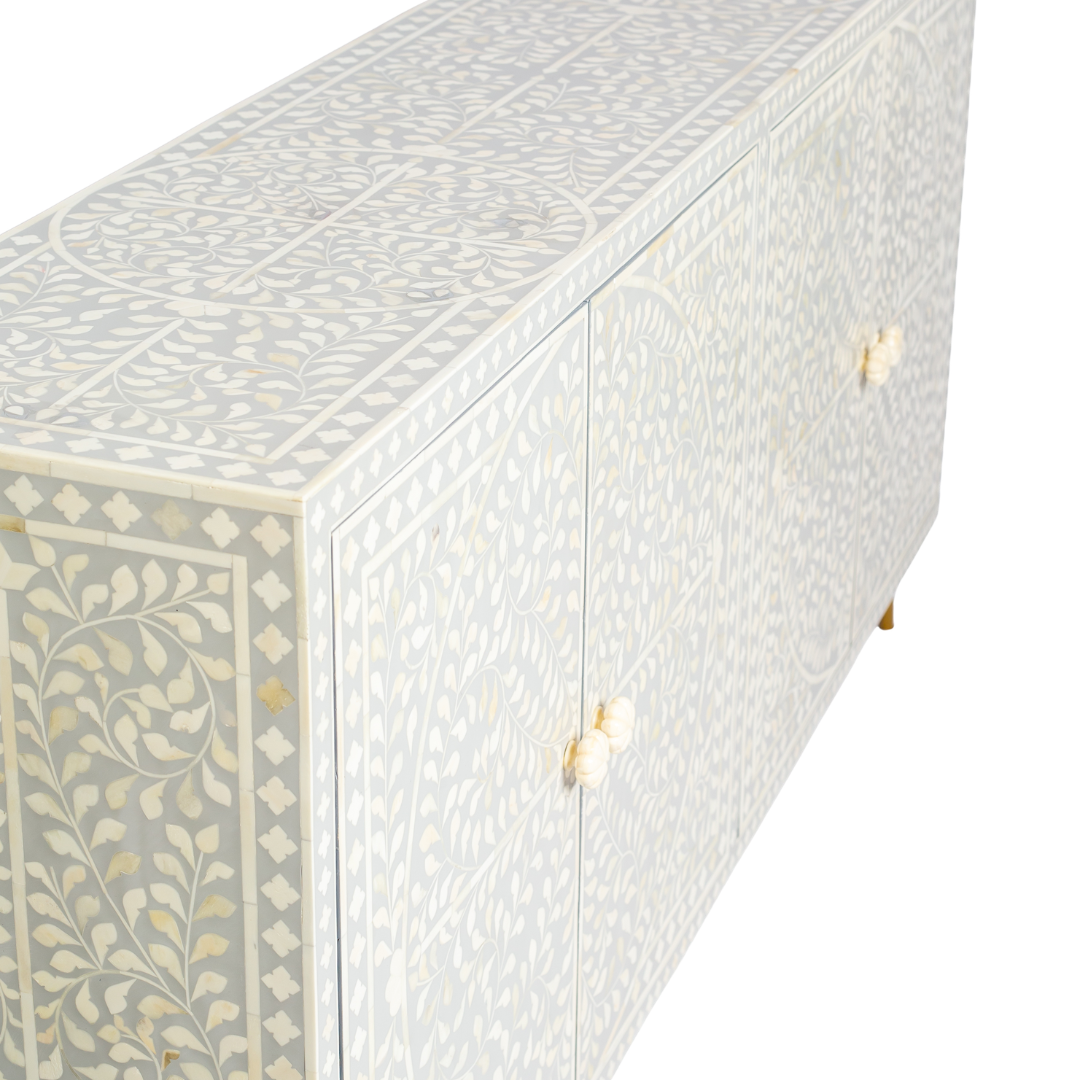Grey bone inlay cabinet with floral vine pattern, brass legs, and carved bone knobs, handcrafted with spacious storage and artisanal charm.