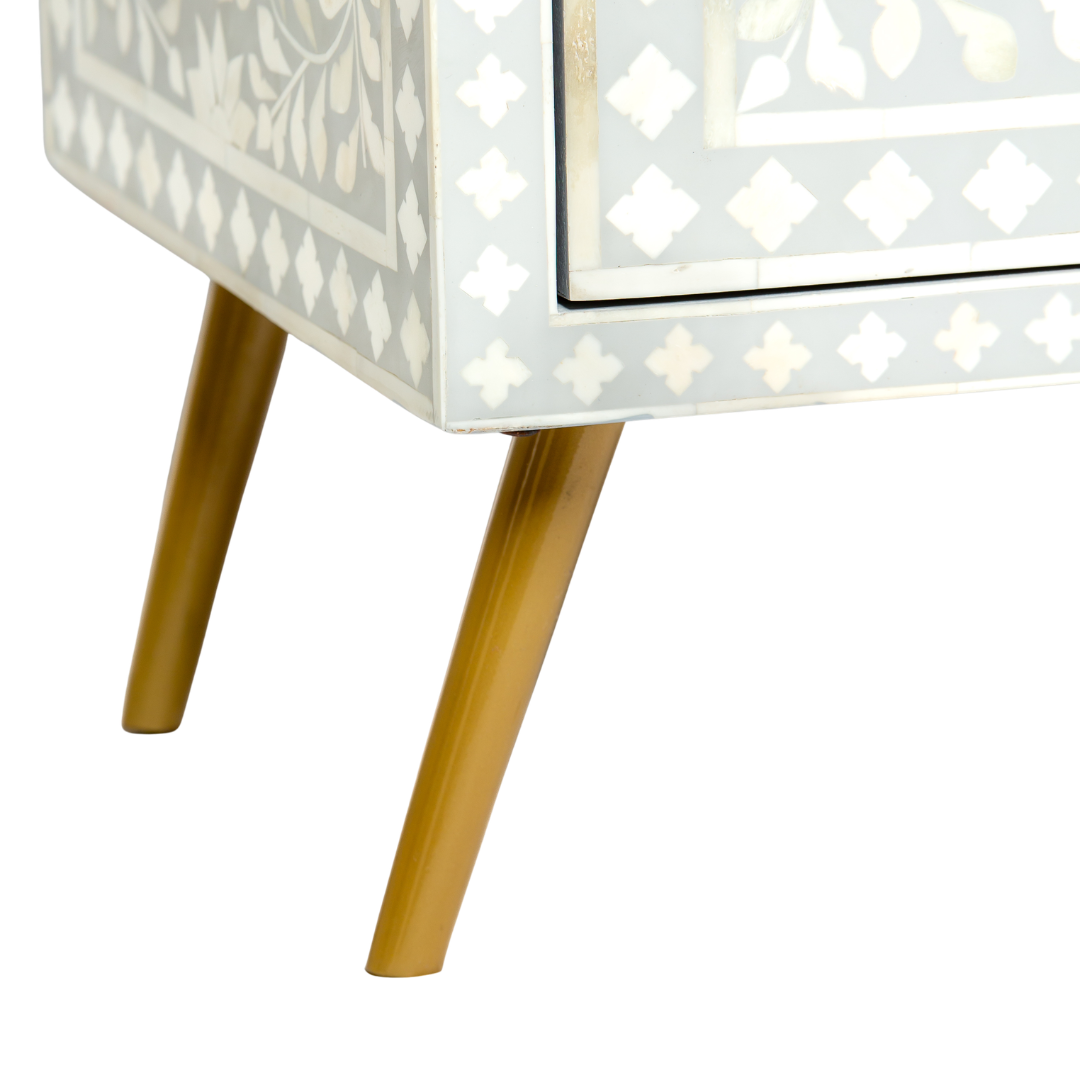 Grey bone inlay cabinet with floral vine pattern, brass legs, and carved bone knobs, handcrafted with spacious storage and artisanal charm.