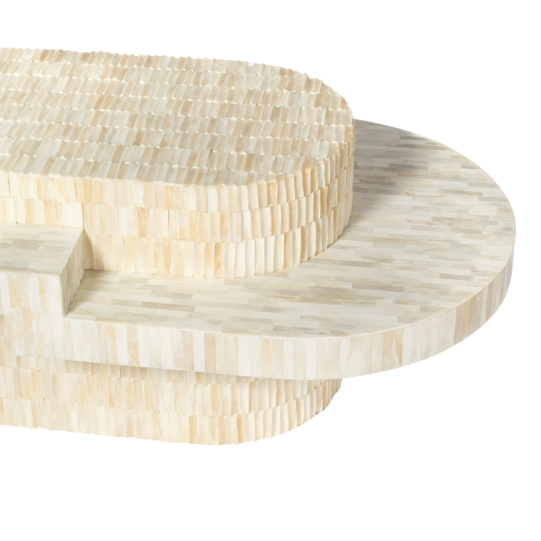 Sculptural bone carved coffee table with layered design in soft neutral tones, handcrafted with curved tiers and textured artisanal detailing.