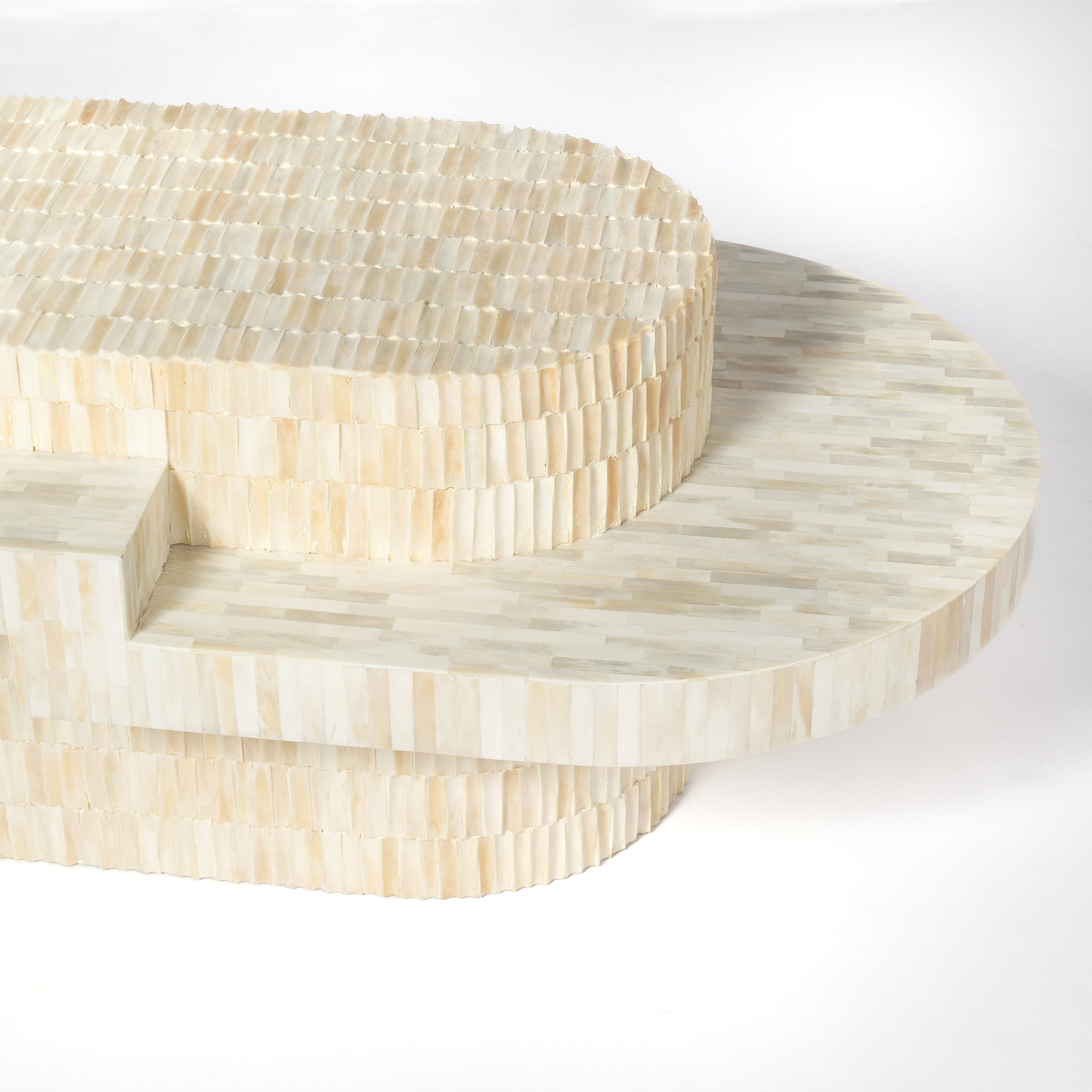 Sculptural bone carved coffee table with layered design in soft neutral tones, handcrafted with curved tiers and textured artisanal detailing.