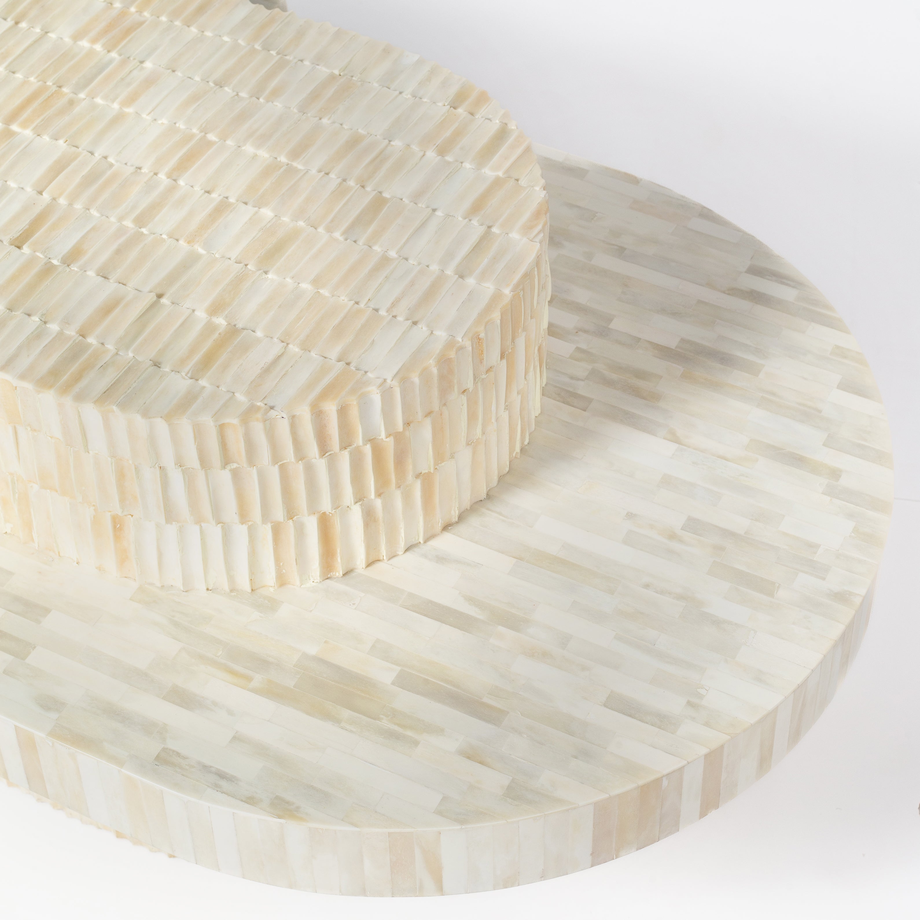 Sculptural bone carved coffee table with layered design in soft neutral tones, handcrafted with curved tiers and textured artisanal detailing.