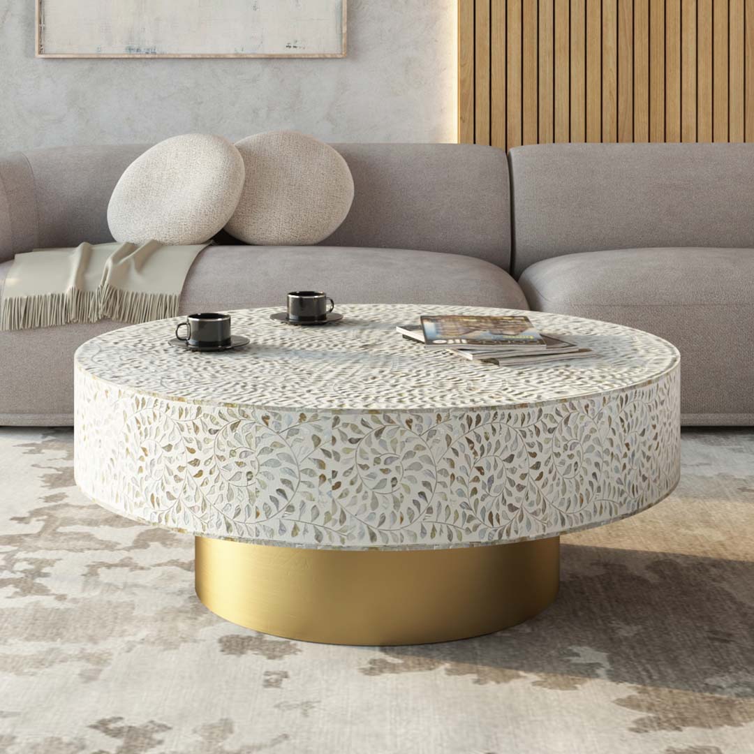 Round white mother of pearl inlay coffee table with floral design and a gold cylindrical base.