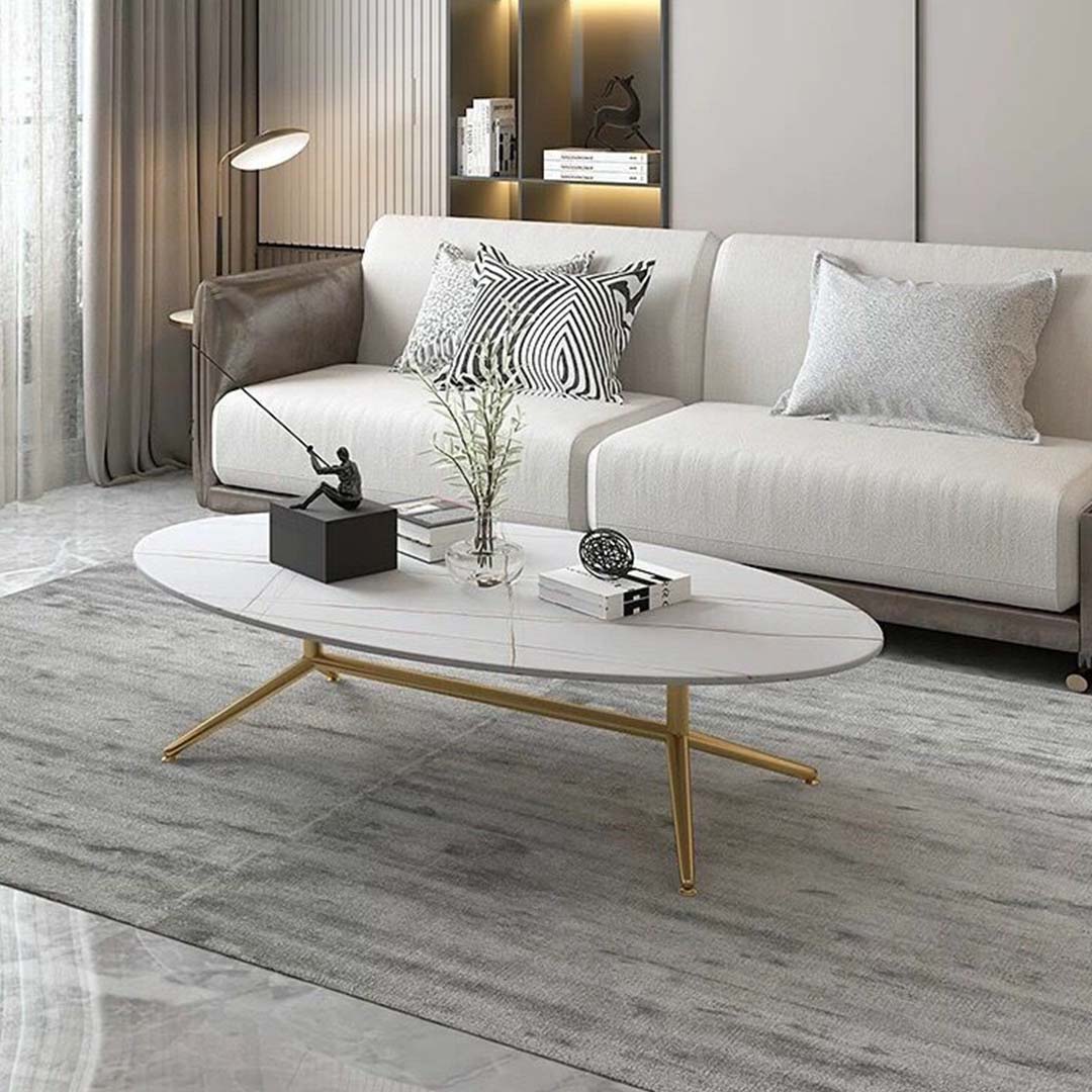 Oval white marble coffee table with subtle gold vein detailing and sleek gold legs. A modern and elegant addition to any living space.