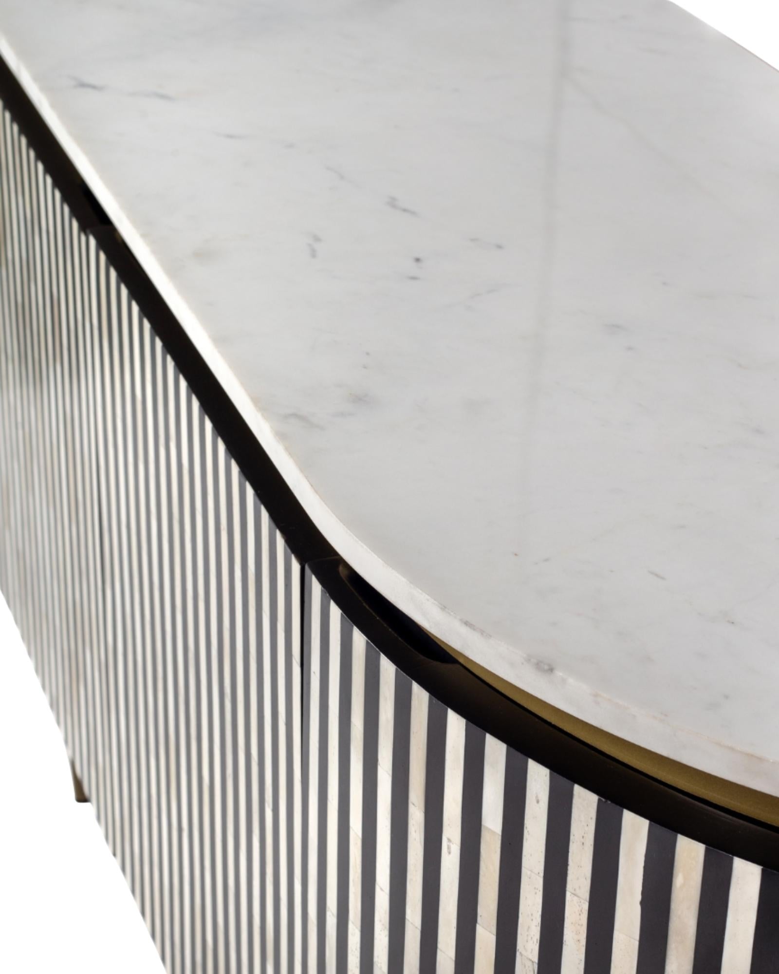 Black bone inlay sideboard with white marble top and brass legs, handcrafted with vertical striping and curved silhouette, luxury interior furniture.