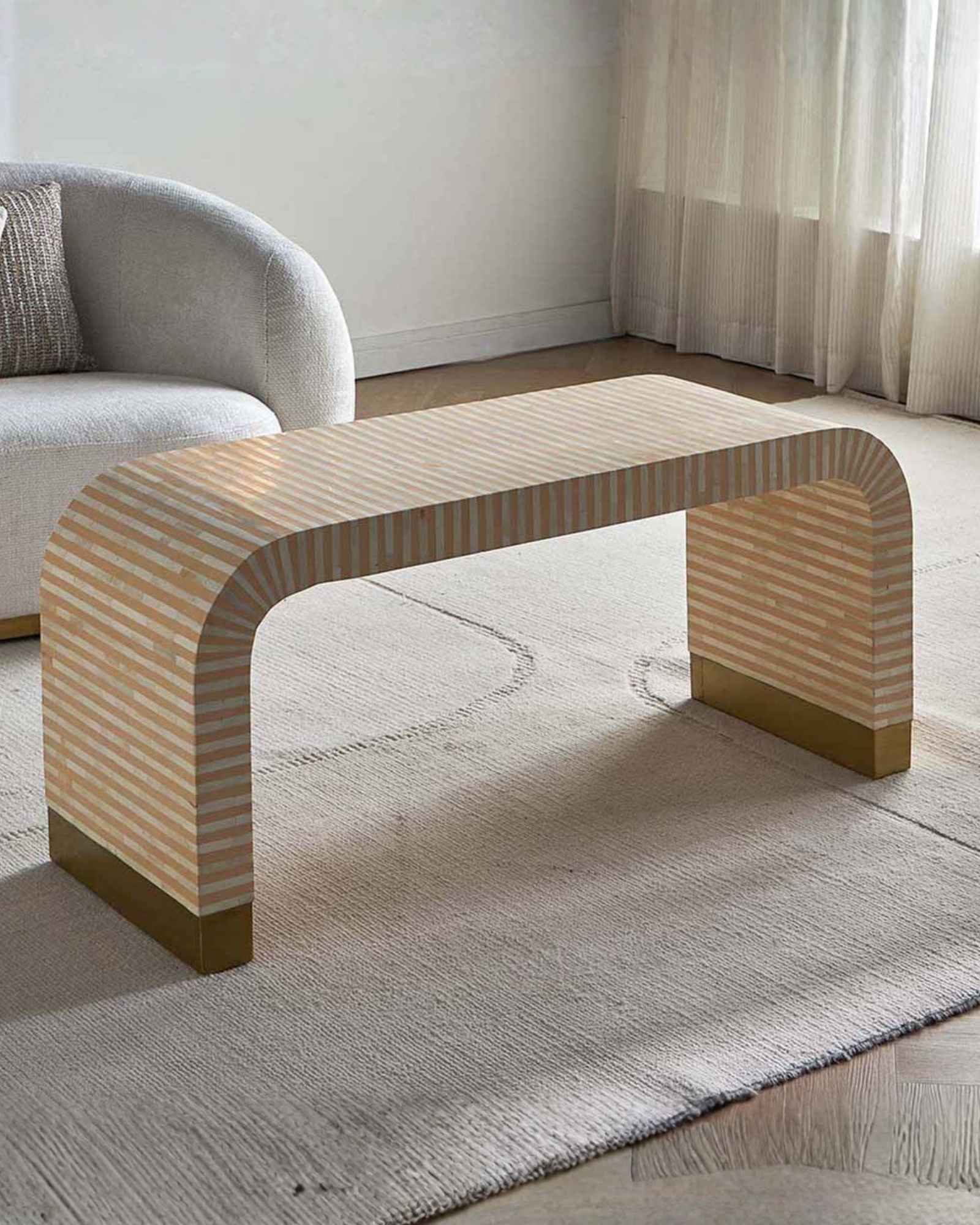 Modern beige bone inlay coffee table with curved edges and gold base. Features a striped inlay design for an elegant aesthetic.