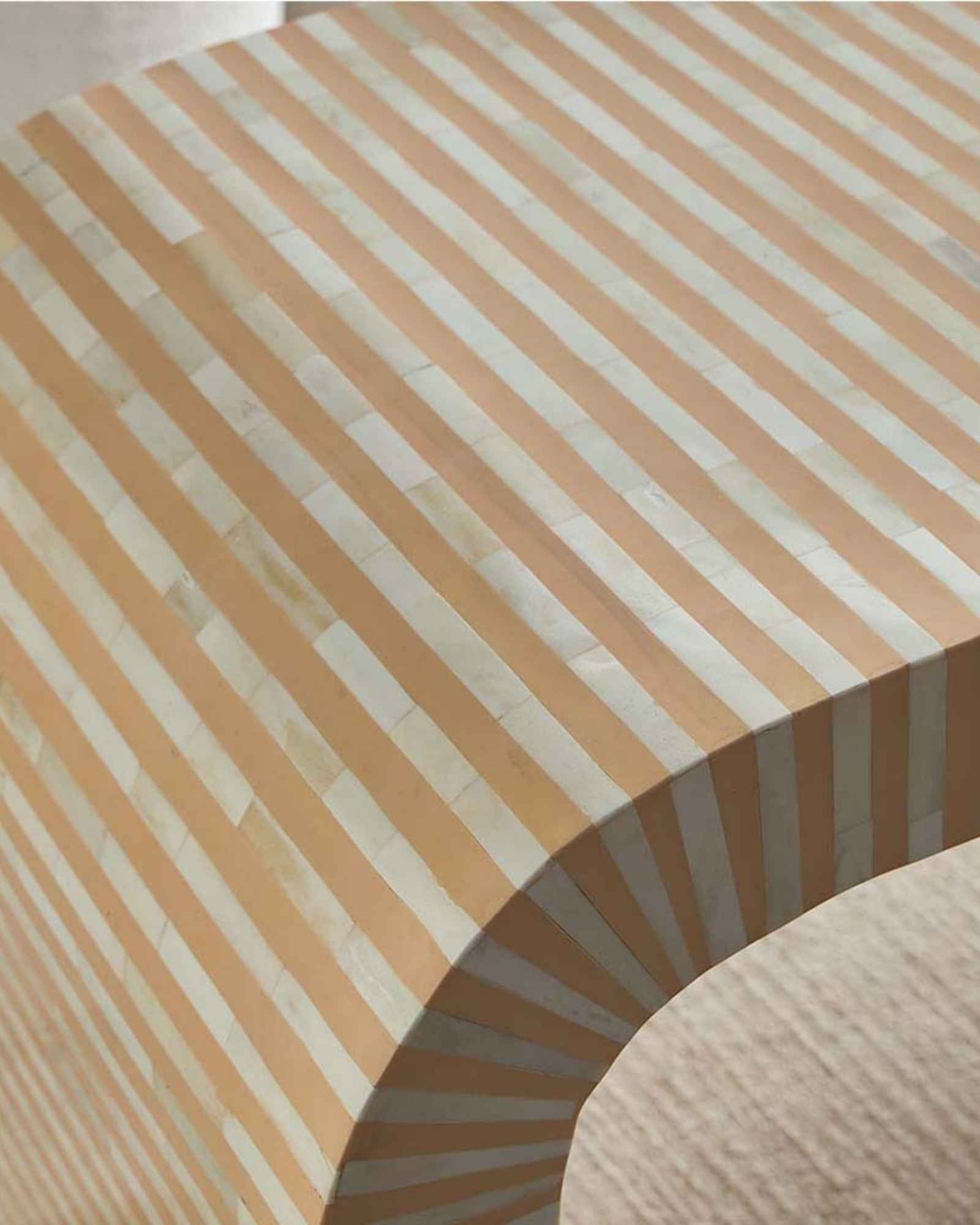 Modern beige bone inlay coffee table with curved edges and gold base. Features a striped inlay design for an elegant aesthetic.