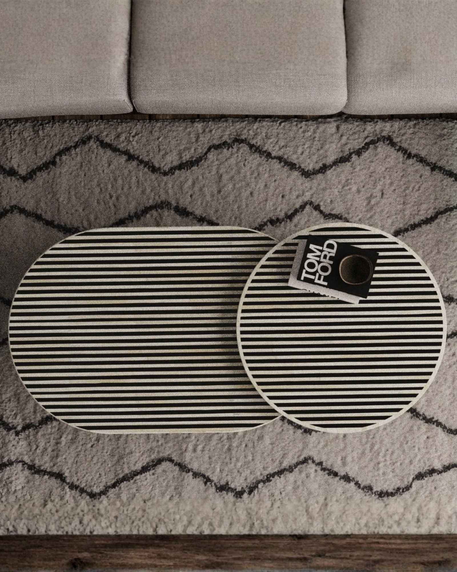 Black bone inlay nesting coffee table with vertical striped pattern and gold base, styled in a modern living room.