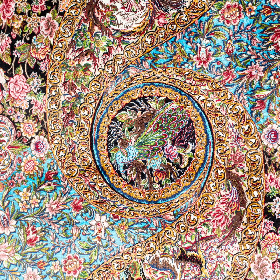 Close-up of the Sevi Persian silk rug featuring a floral and bird pattern in navy, turquoise, and gold tones. 150x100 cm size.