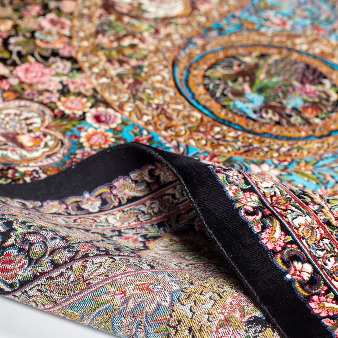 Close-up of the Sevi Persian silk rug featuring a floral and bird pattern in navy, turquoise, and gold tones. 150x100 cm size.