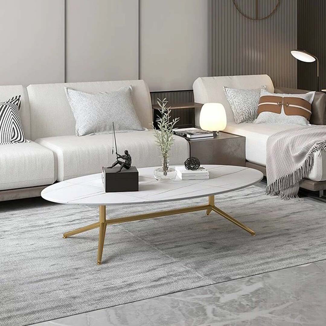 Oval white marble coffee table with subtle gold vein detailing and sleek gold legs.