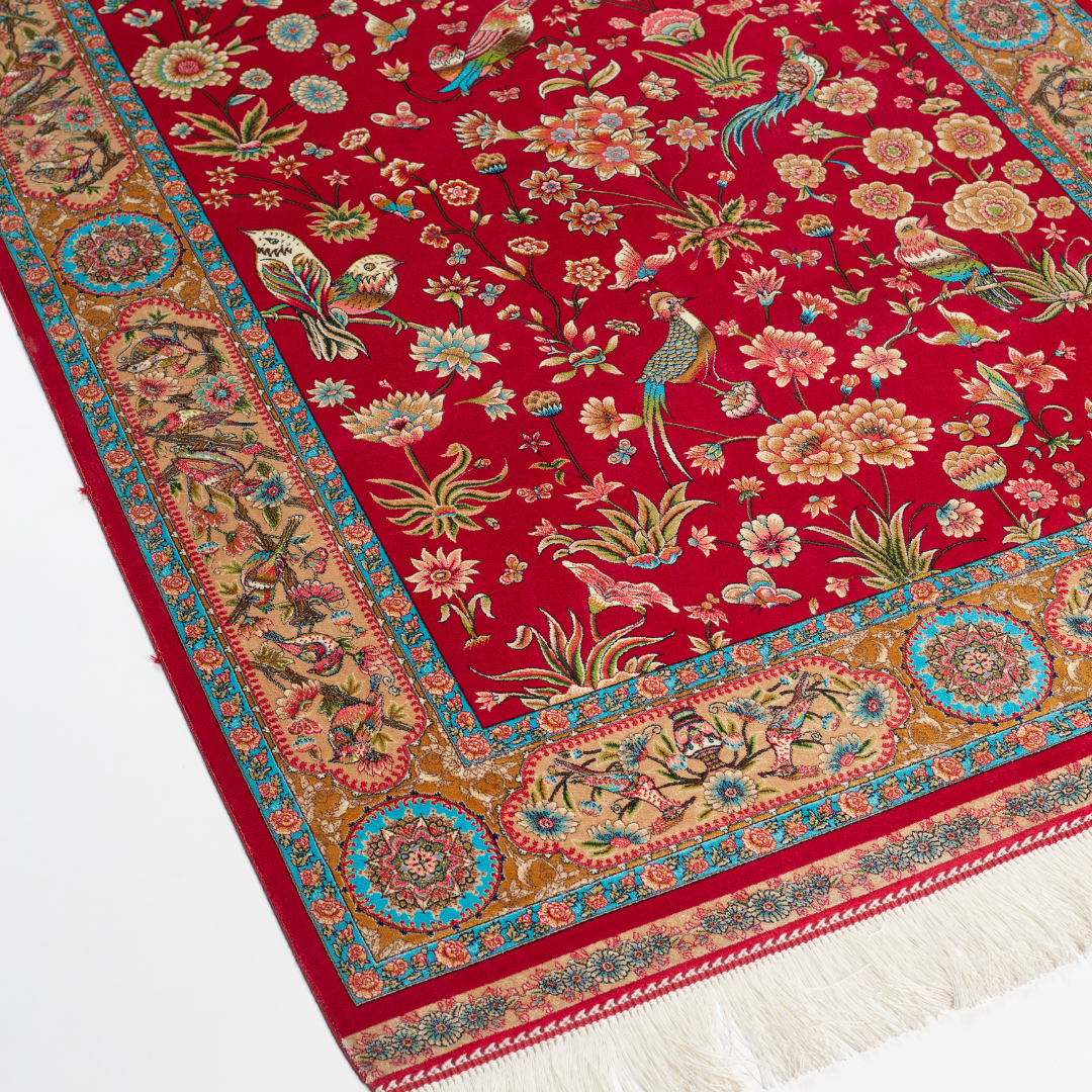 Crimson red silk rug featuring multi-colour floral and bird motifs, accented with turquoise, ivory, and gold detailing.