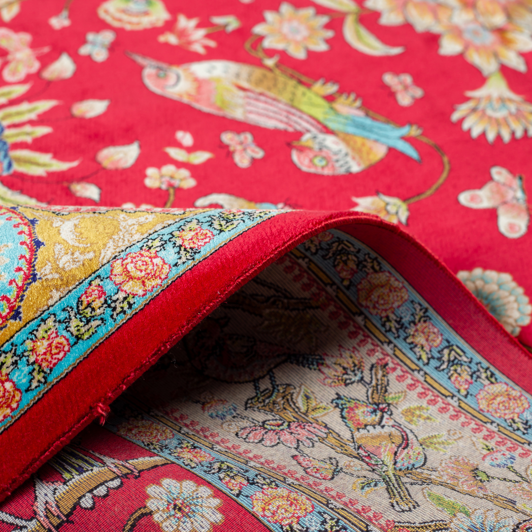 Crimson red silk rug featuring multi-colour floral and bird motifs, accented with turquoise, ivory, and gold detailing.