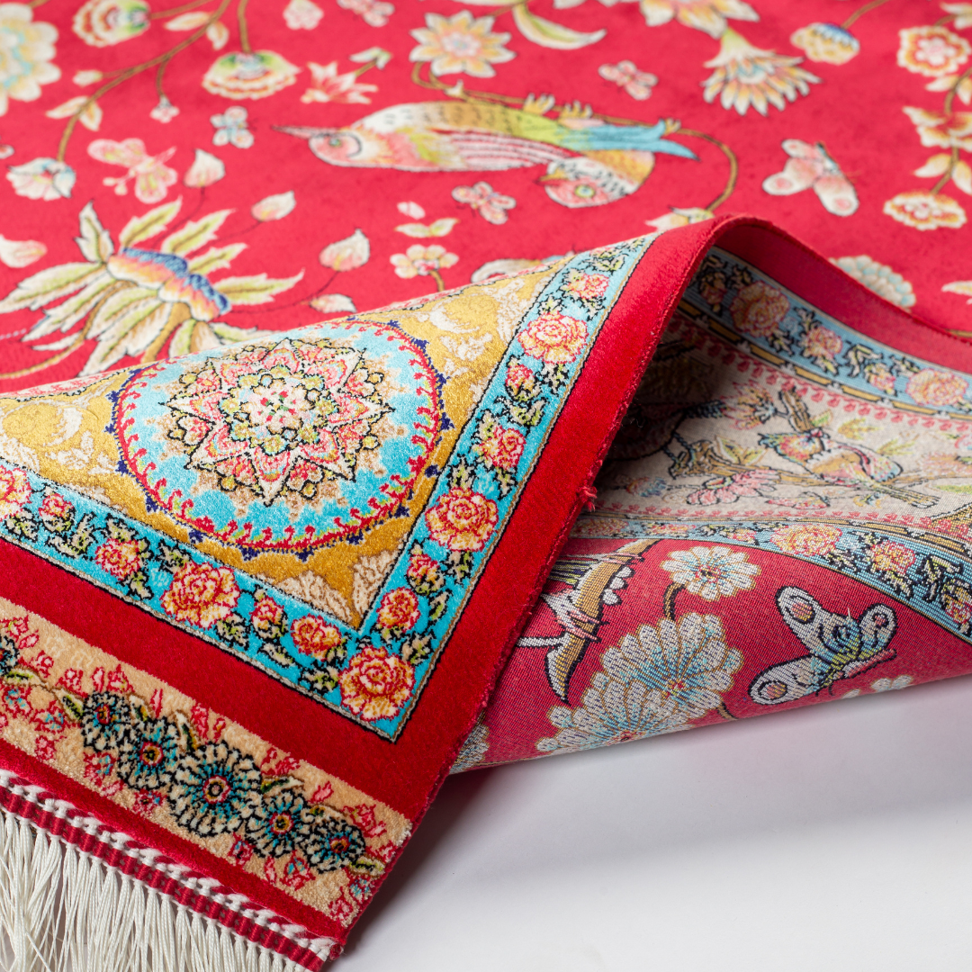 Crimson red silk rug featuring multi-colour floral and bird motifs, accented with turquoise, ivory, and gold detailing.