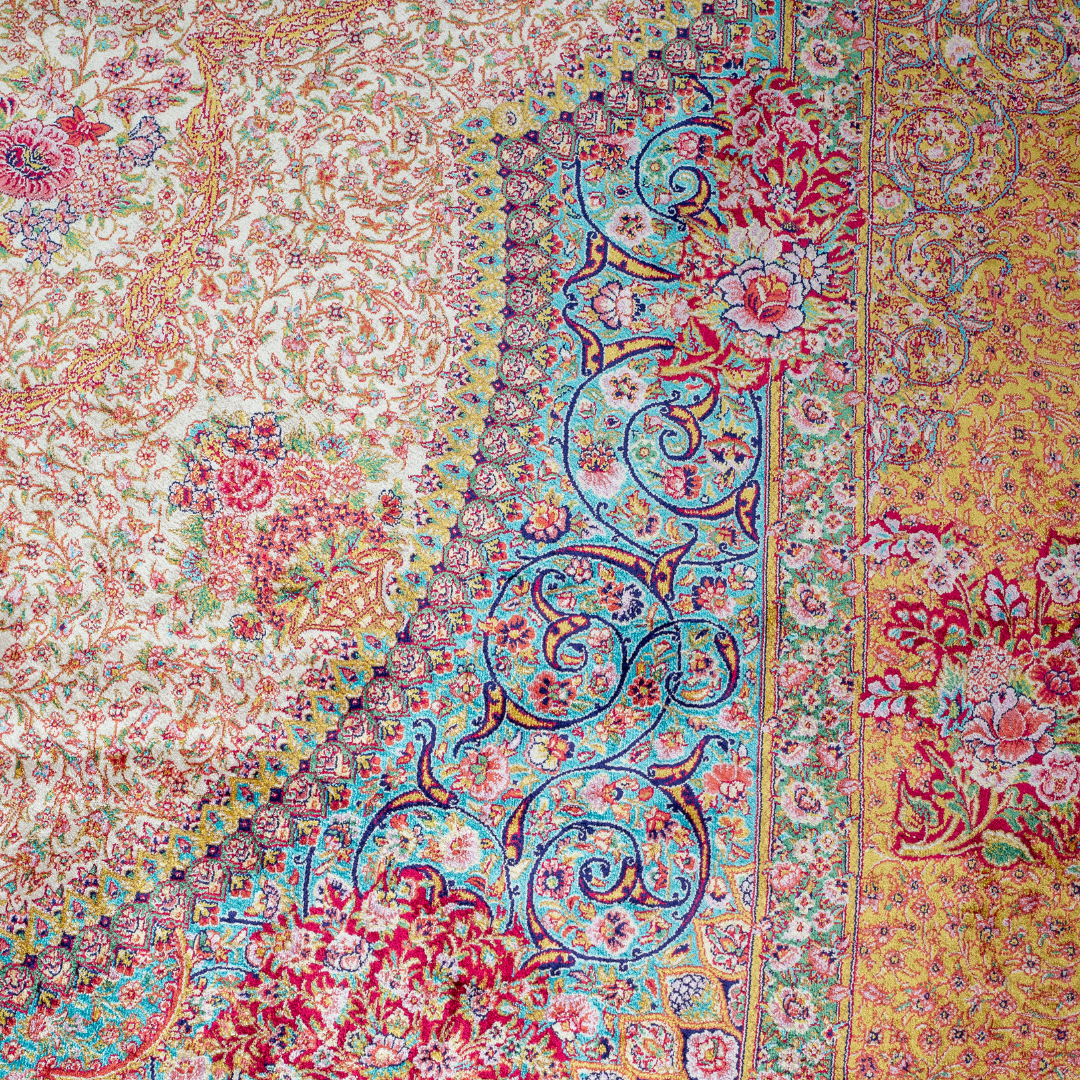 Silk Persian rug with a floral rosette medallion, ivory base, and ornate border in saffron, turquoise, plum, and blush tones.