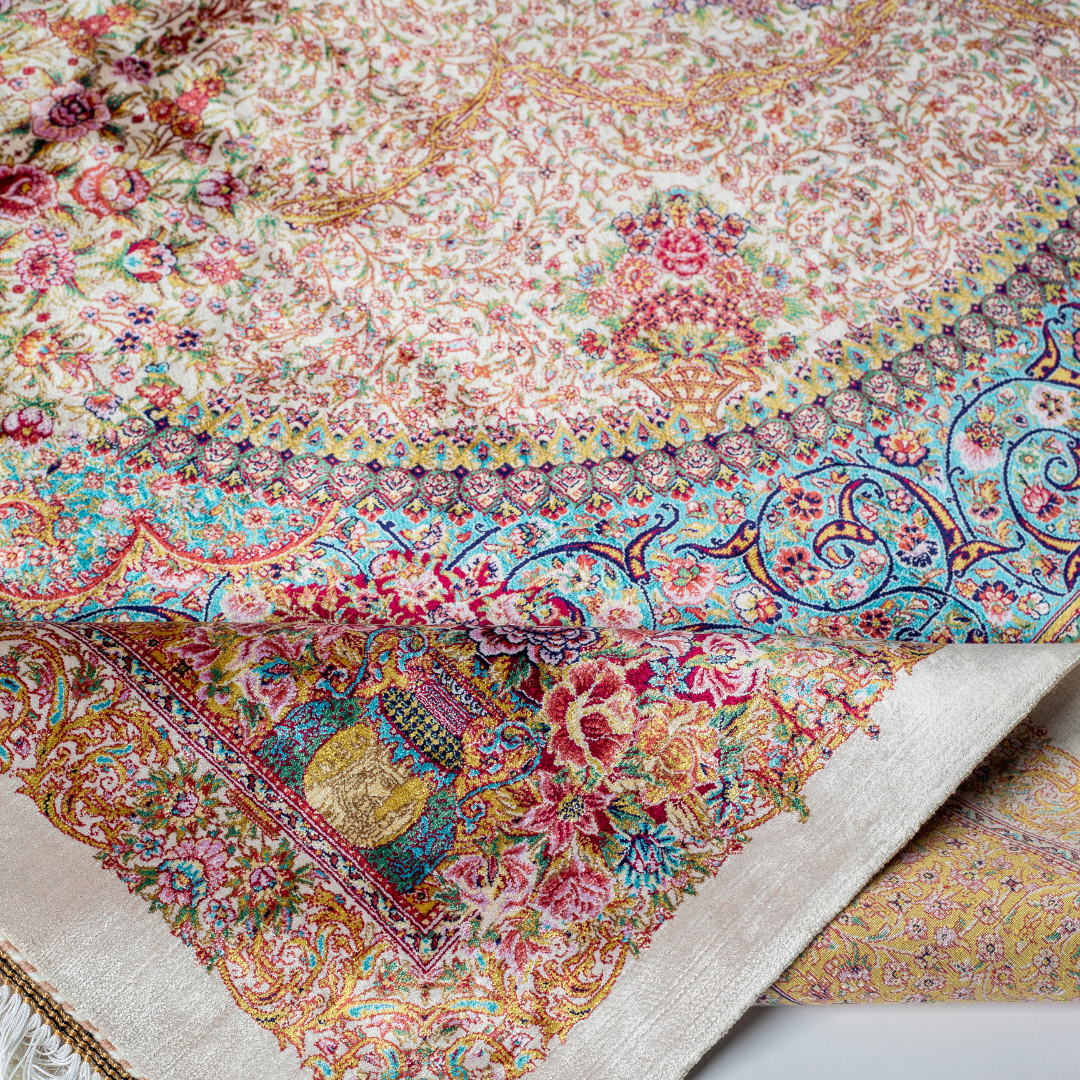 Silk Persian rug with a floral rosette medallion, ivory base, and ornate border in saffron, turquoise, plum, and blush tones.