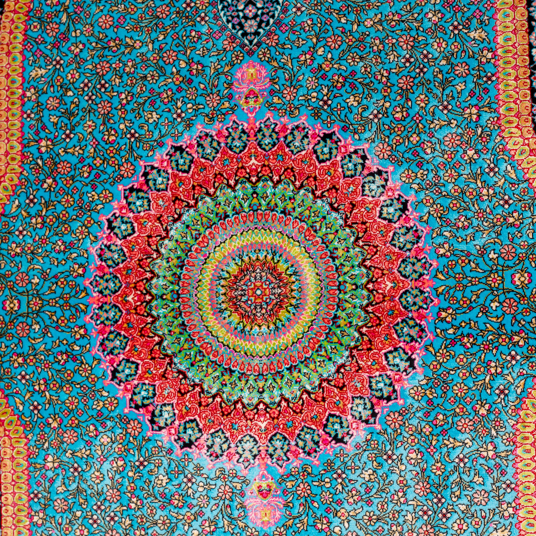 Vortex Silk Rug featuring a central floral medallion on a turquoise base with red, green, and black detailing, size 150x100 cm.