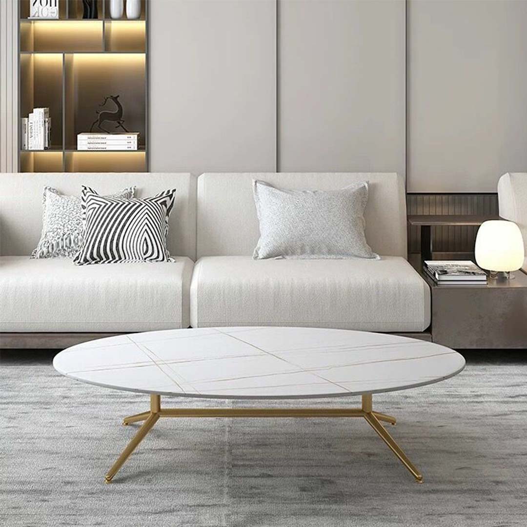 Oval white marble coffee table with subtle gold vein detailing and sleek gold legs
