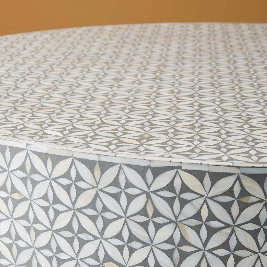 Round grey bone inlay coffee table with floral design and a bold gold base. A stylish and modern centerpiece for any living room.