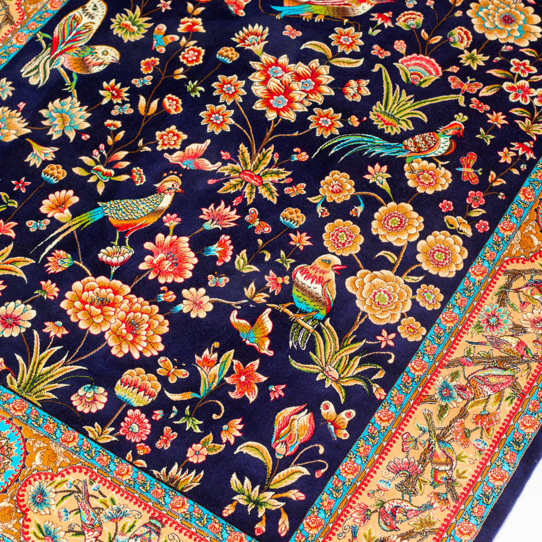 Zian silk rug featuring navy base with multi-colour florals and birds, hand-finished with detailed borders.