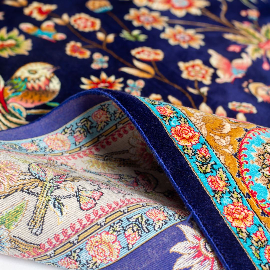 Zian silk rug featuring navy base with multi-colour florals and birds, hand-finished with detailed borders.
