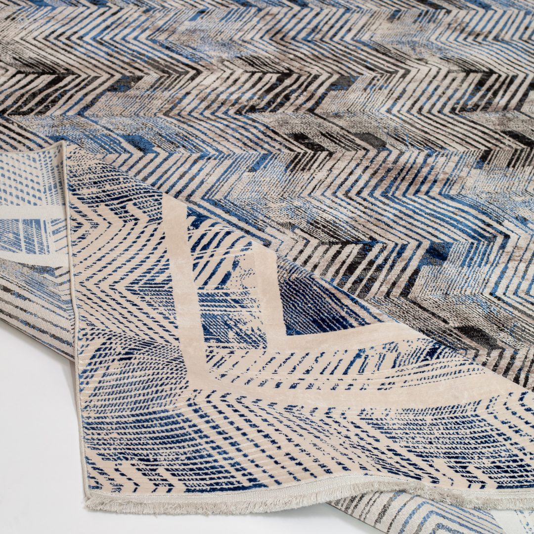 Zira cotton rug featuring a bold chevron pattern in grey, blue, and ivory with a distressed texture, perfect for contemporary interiors.