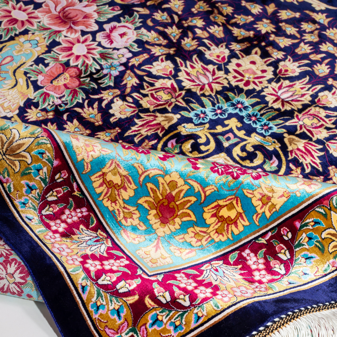 The Amorette silk rug features an ornate floral medallion over a navy base, with vivid accents of turquoise, gold, and crimson in 350x250 cm.