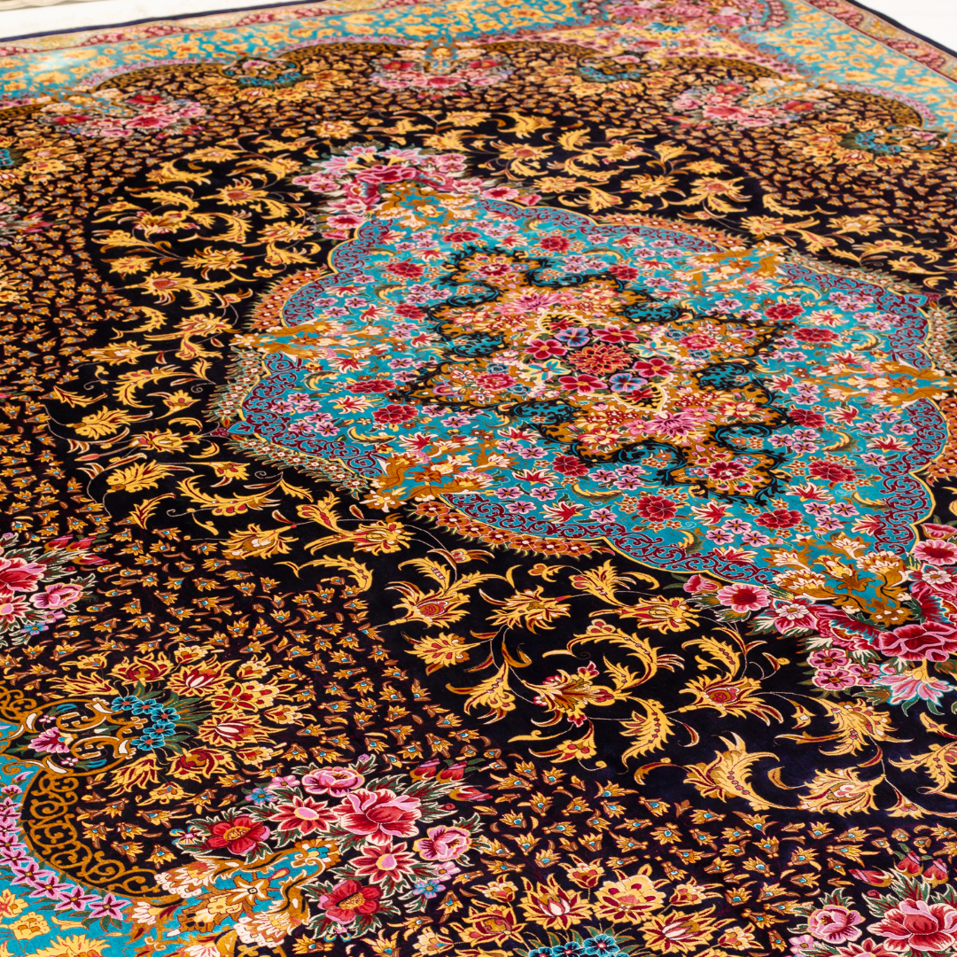 The Amorette silk rug features an ornate floral medallion over a navy base, with vivid accents of turquoise, gold, and crimson in 350x250 cm.