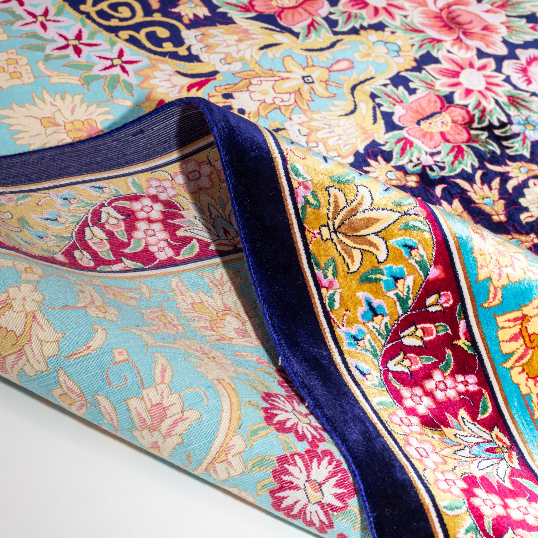 The Amorette silk rug features an ornate floral medallion over a navy base, with vivid accents of turquoise, gold, and crimson in 350x250 cm.