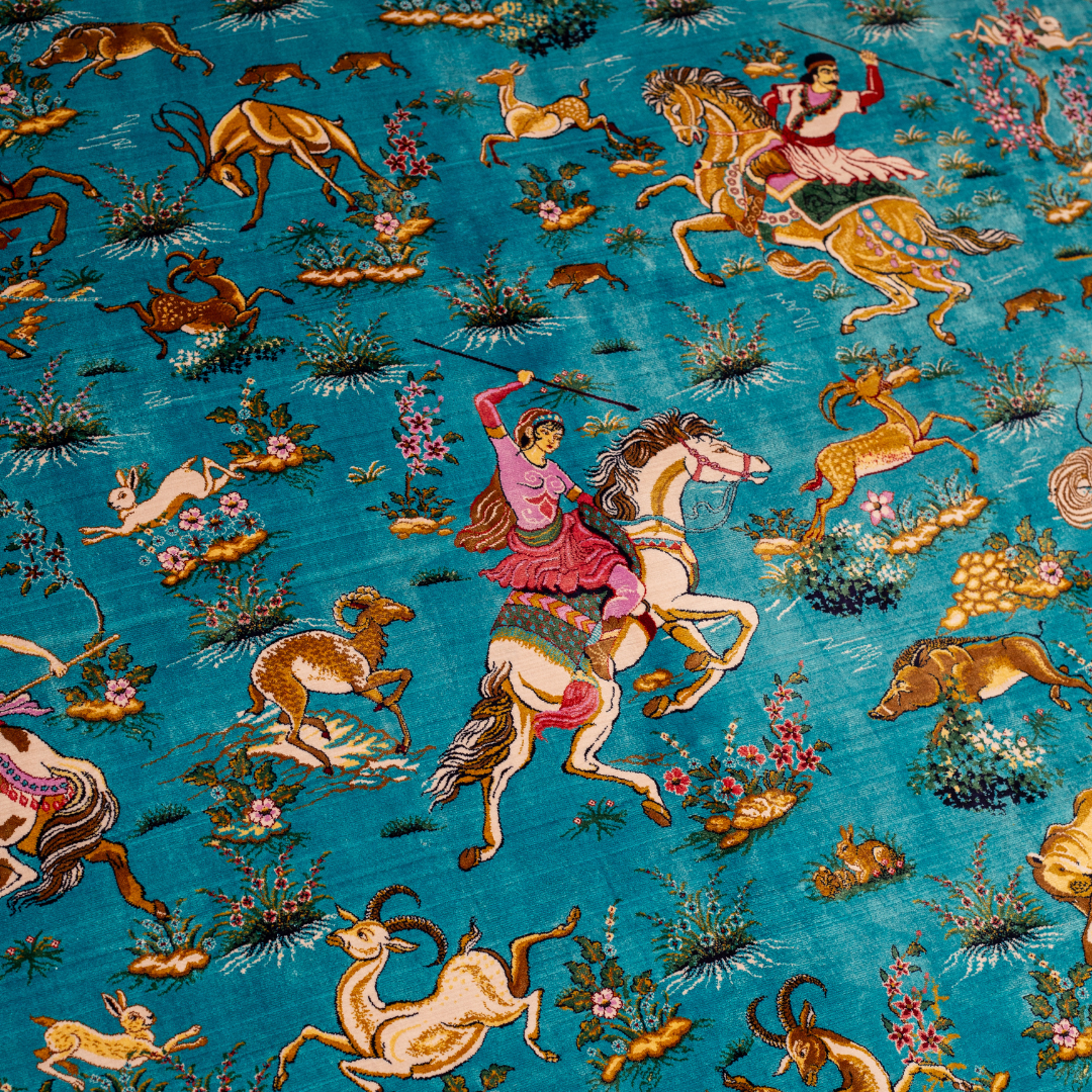 Vibrant handwoven silk rug with a turquoise base, animal motifs, hunting scenes, and floral detailing in gold and pink tones.