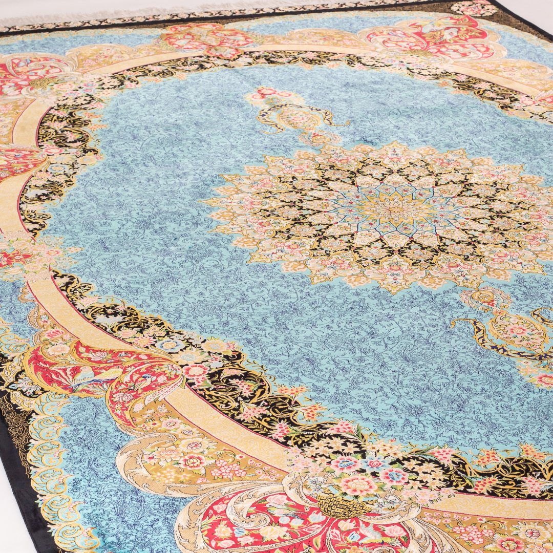 Luxury blue silk rug featuring a detailed central medallion, floral motifs, and ornate bird patterns in gold, coral, and black accents.