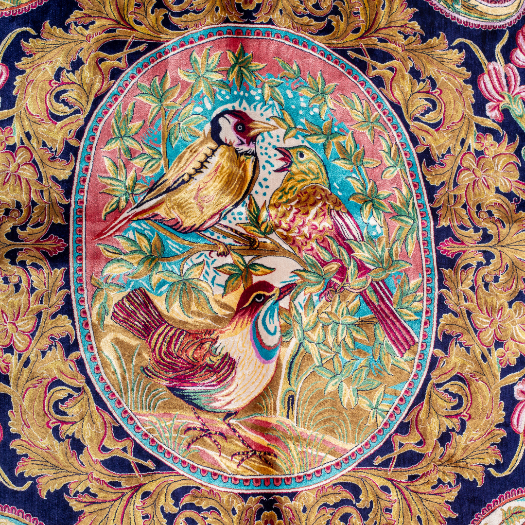 Silk rug with tree of life and bird motif, burgundy floral base, and ornate navy-gold borders. Handwoven with artistic precision.