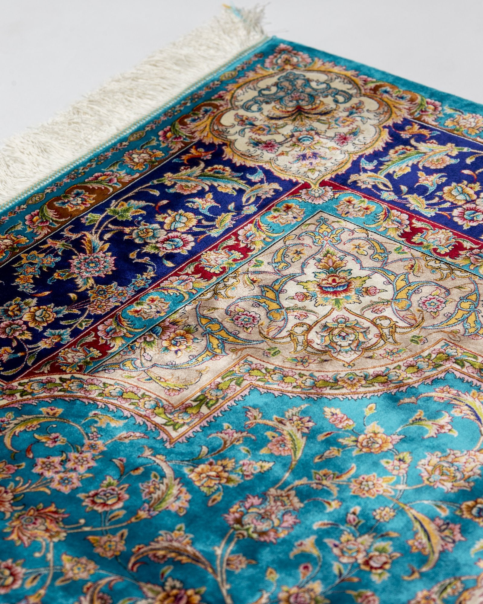 angled view with a fringed end on the Marina turquoise silk rug