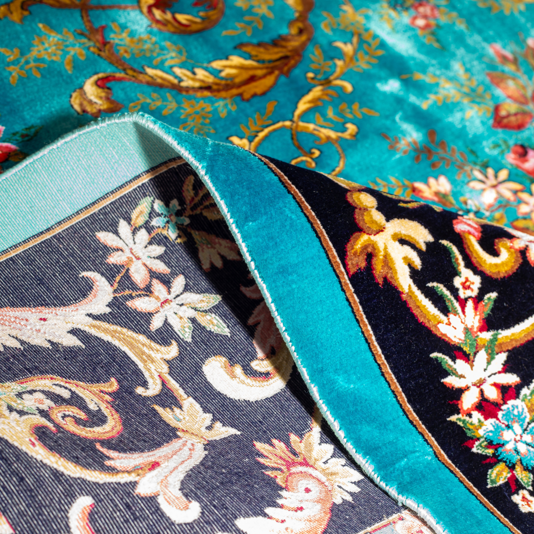 The Bellamy silk rug in turquoise with red floral motifs and golden scrolls, featuring a black ornamental border and exquisite handwoven detailing.