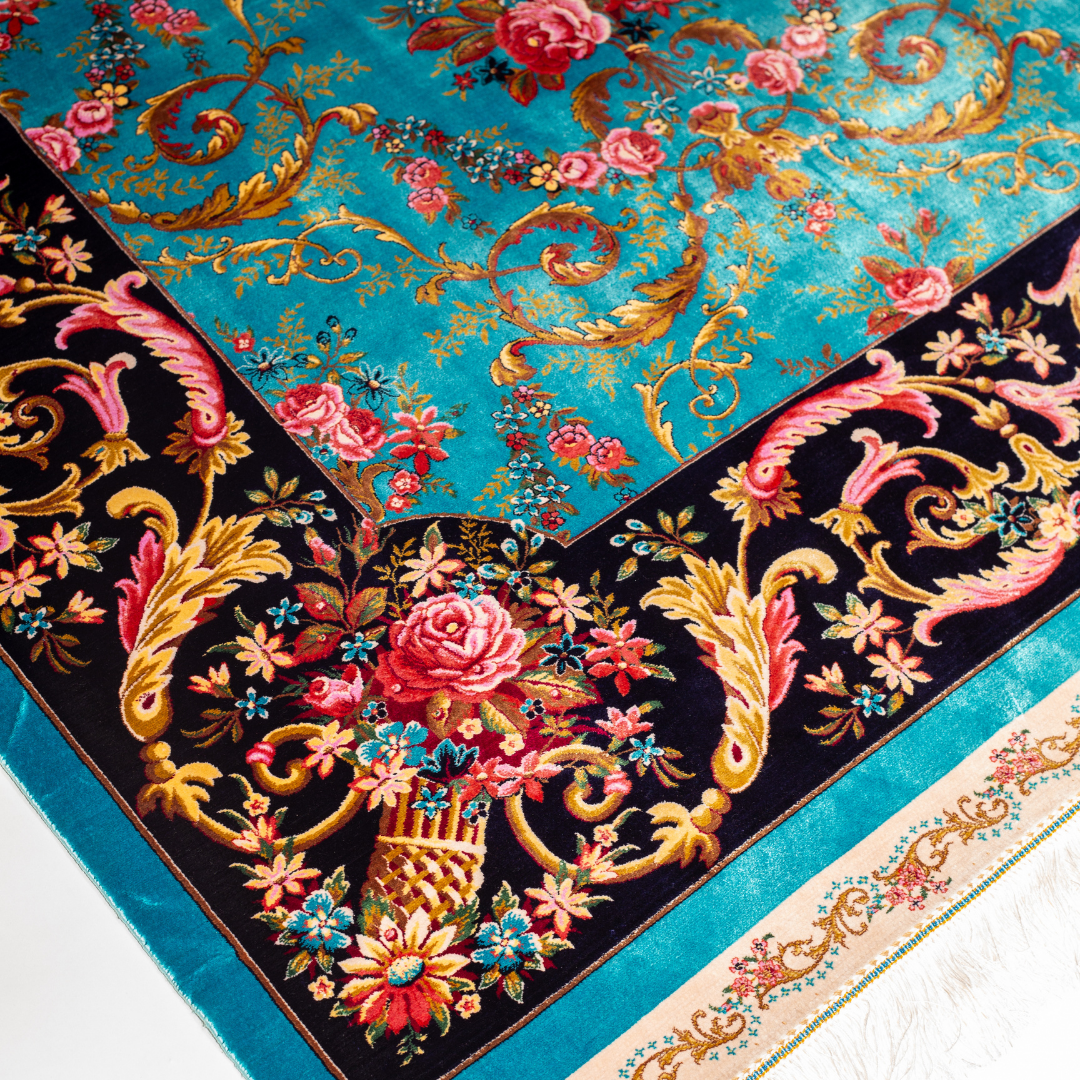 The Bellamy silk rug in turquoise with red floral motifs and golden scrolls, featuring a black ornamental border and exquisite handwoven detailing.