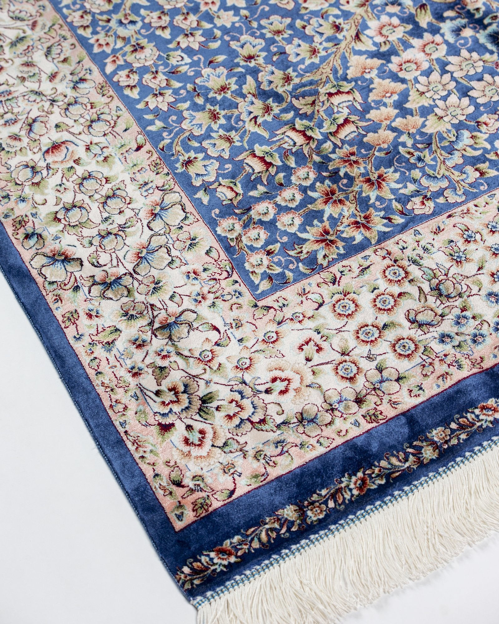 angled view with a fringed end on the Delkash blue silk rug