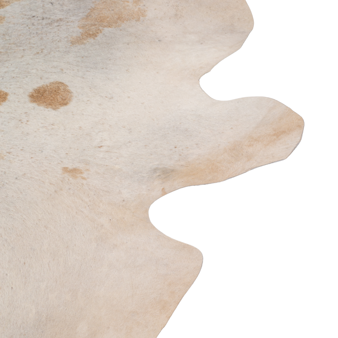 Natural cowhide rug with beige and chestnut brown markings, organic shape, and smooth textured finish.