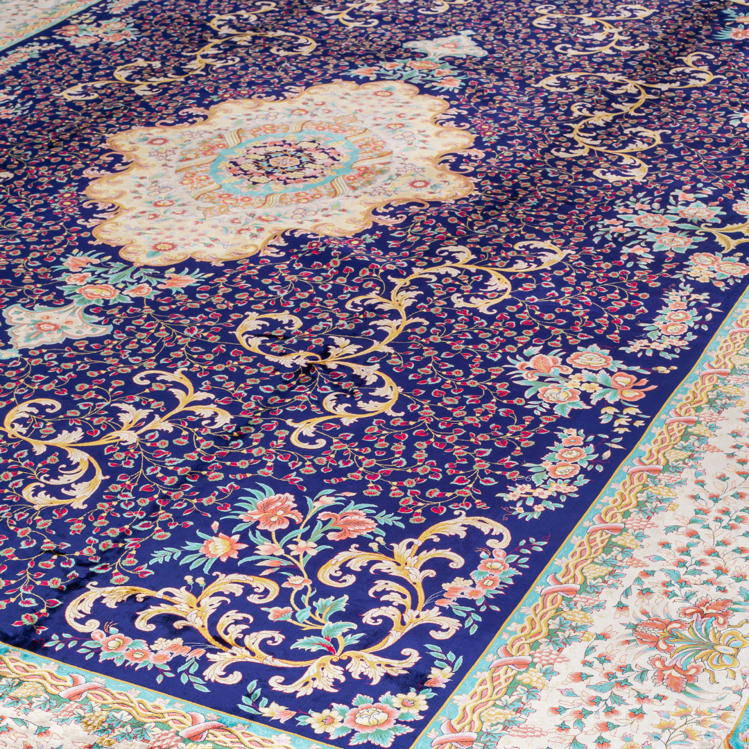 Elegant navy silk rug with detailed floral medallion, ornate cream border, and rich Persian-inspired design in gold, coral, and turquoise tones.