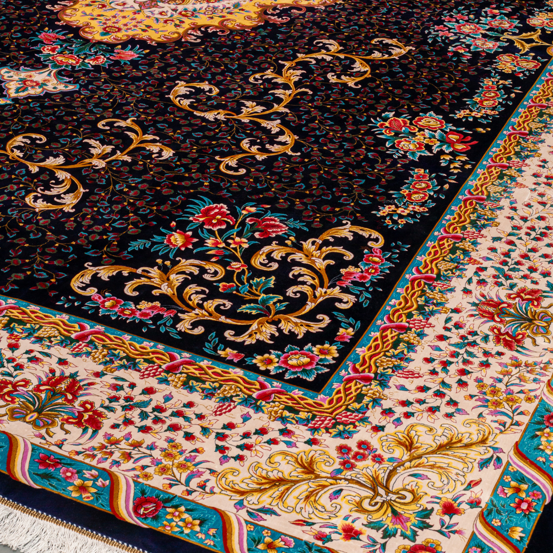 Elegant navy silk rug with detailed floral medallion, ornate cream border, and rich Persian-inspired design in gold, coral, and turquoise tones.