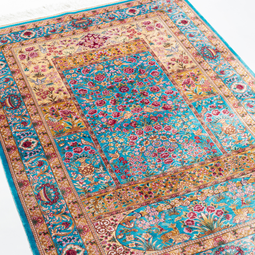 Neriah Silk Rug featuring ruby red floral and bird motifs on an aqua-blue base with golden ornate panels, size 150x100 cm.
