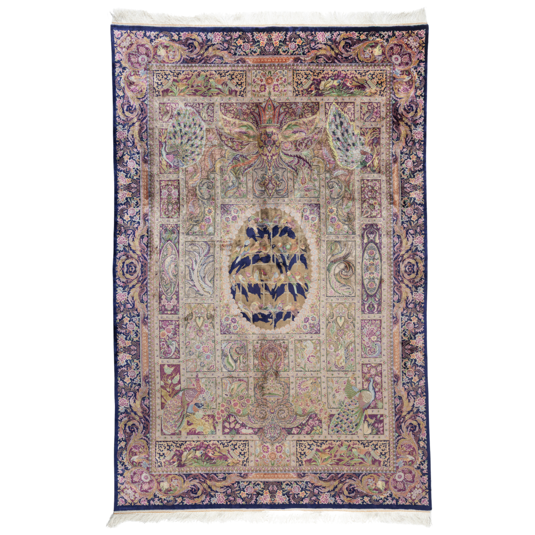 Luxurious silk rug with central bird tree, bordered by peacocks and florals. Handwoven in soft jewel tones with ornate framed details.